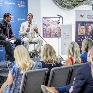 Zachariah Collett speaking to a seated audience at the Portraits of Courage exhibition