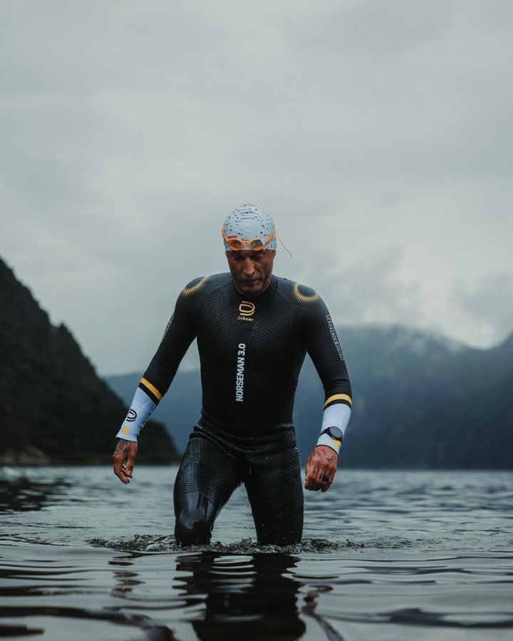 Zachariah Collett walking out of a fjord in a wetsuit after an open-water swim