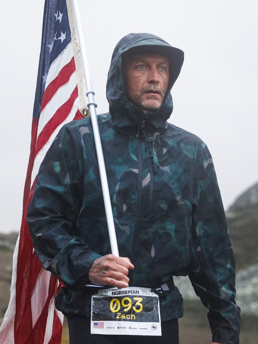 Zachariah Collett carrying the United States flag in the rain during the Norseman Xtreme Triathlon